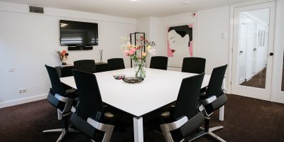 Moderne vergaderruimte 'Apollo' bij EBC Amsterdam met een grote vierkante tafel, ergonomische stoelen en stijlvolle wanddecoratie.