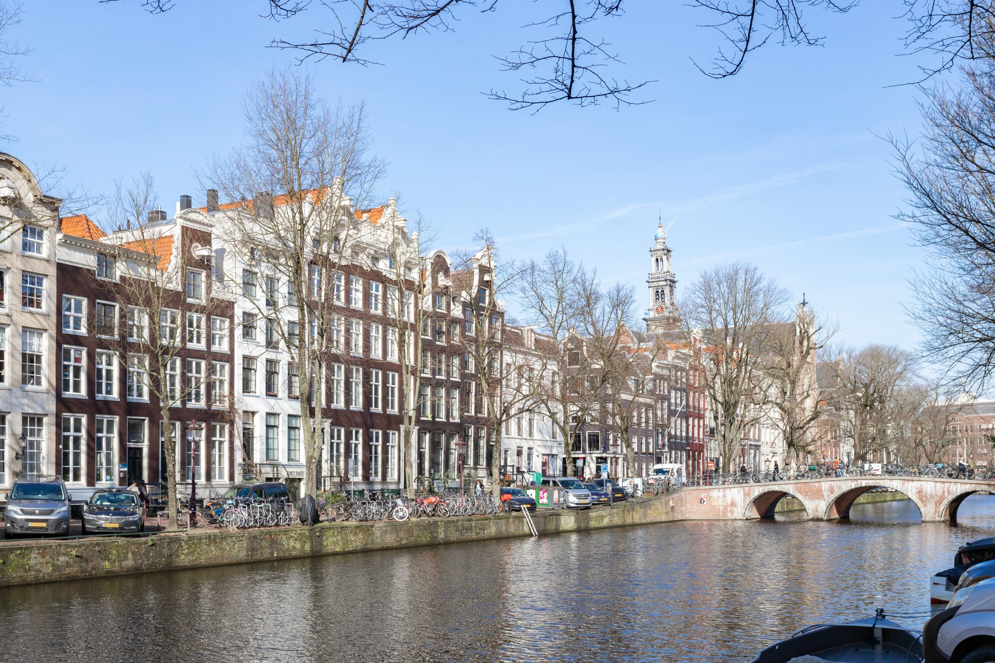 Panoramisch uitzicht op historische grachtenpanden aan de Keizersgracht in Amsterdam met de Westerkerk op de achtergrond.